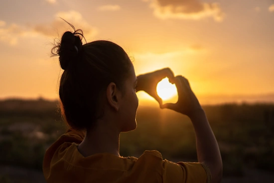 una mujer haciendo con sus manos un corazón potque sabe cómo tener amor propio